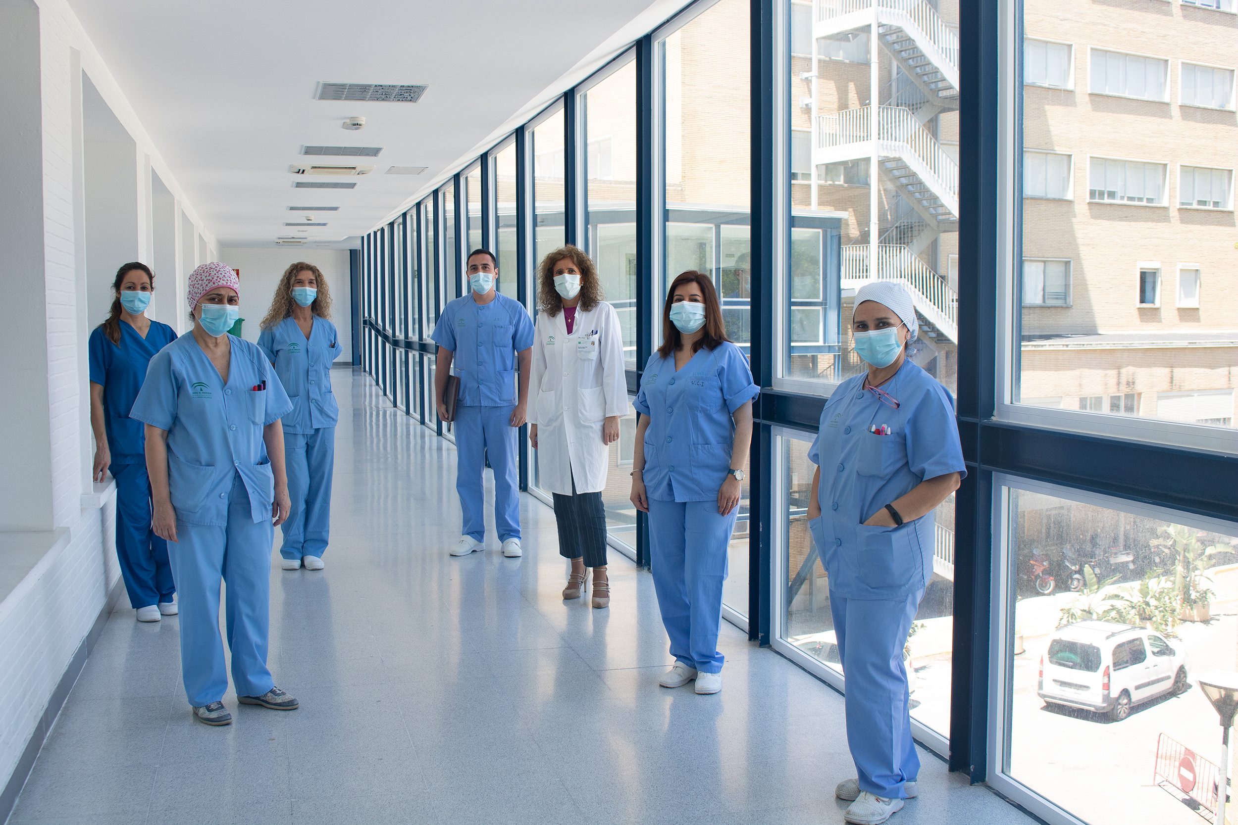un grupo de profesionales de la UCI posa en el pasillo que une los hospitales